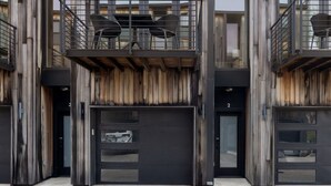 A modern building with a wooden facade, multiple balconies, and a flat roof.