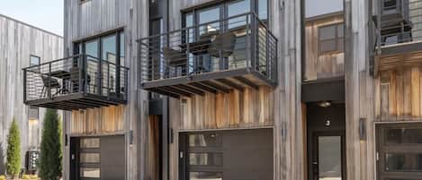 Un immeuble moderne à plusieurs étages, doté de grandes fenêtres, de balcons et d’une entrée de garage.