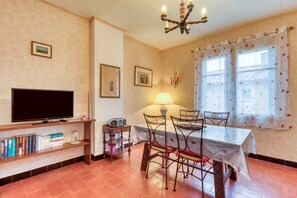Ein Essbereich mit Tisch, Stühlen, einem Fernseher, Büchern und einer Lampe.