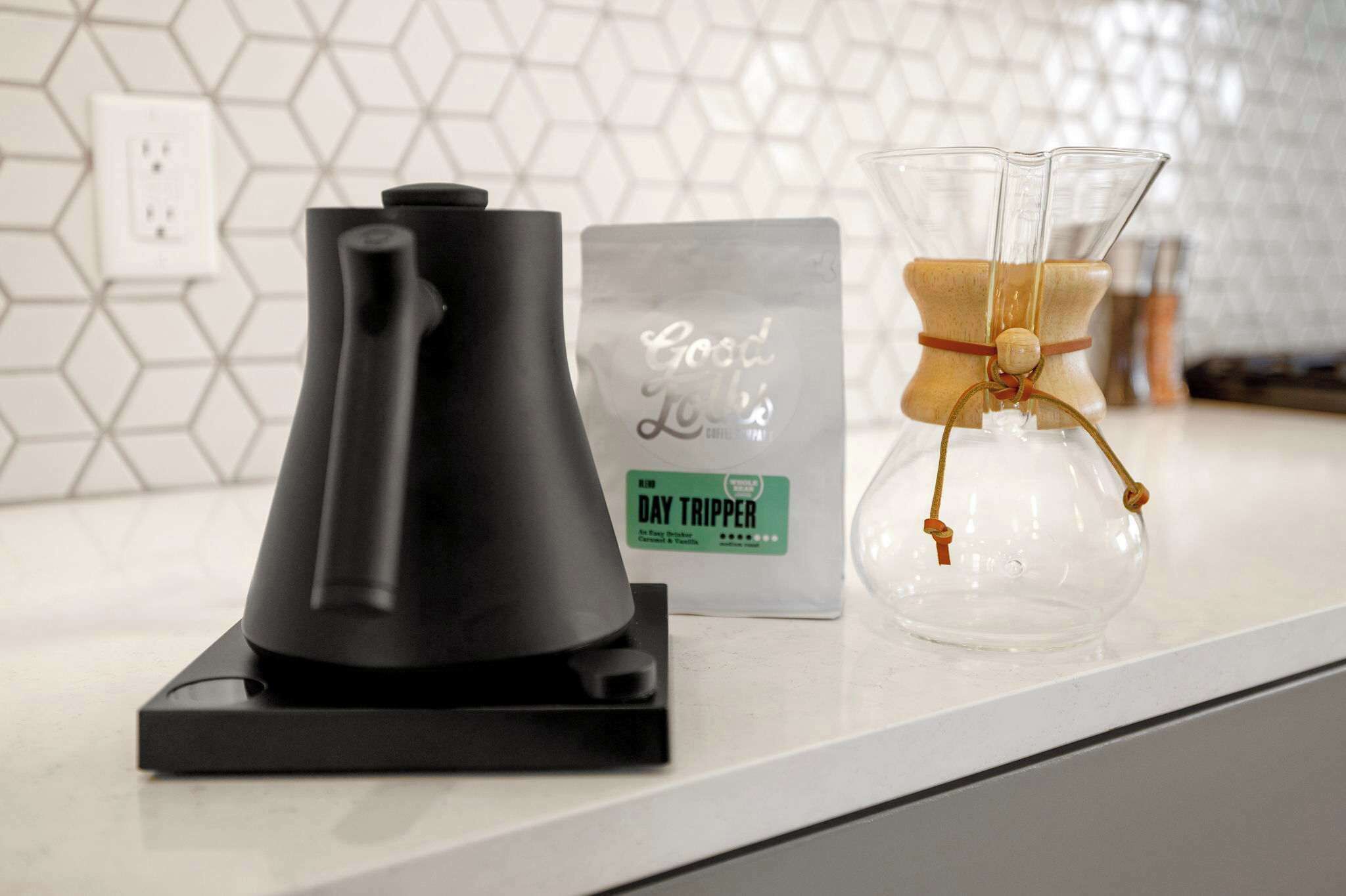 Una cafetera, una bolsa de viaje y un frasco de vidrio con un hilo sobre una encimera de cocina.