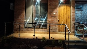 A building with a brick facade, a wooden door labeled "JLLA 14", and a metal railing in front. - Sandalwoods Resorts (Karjat)