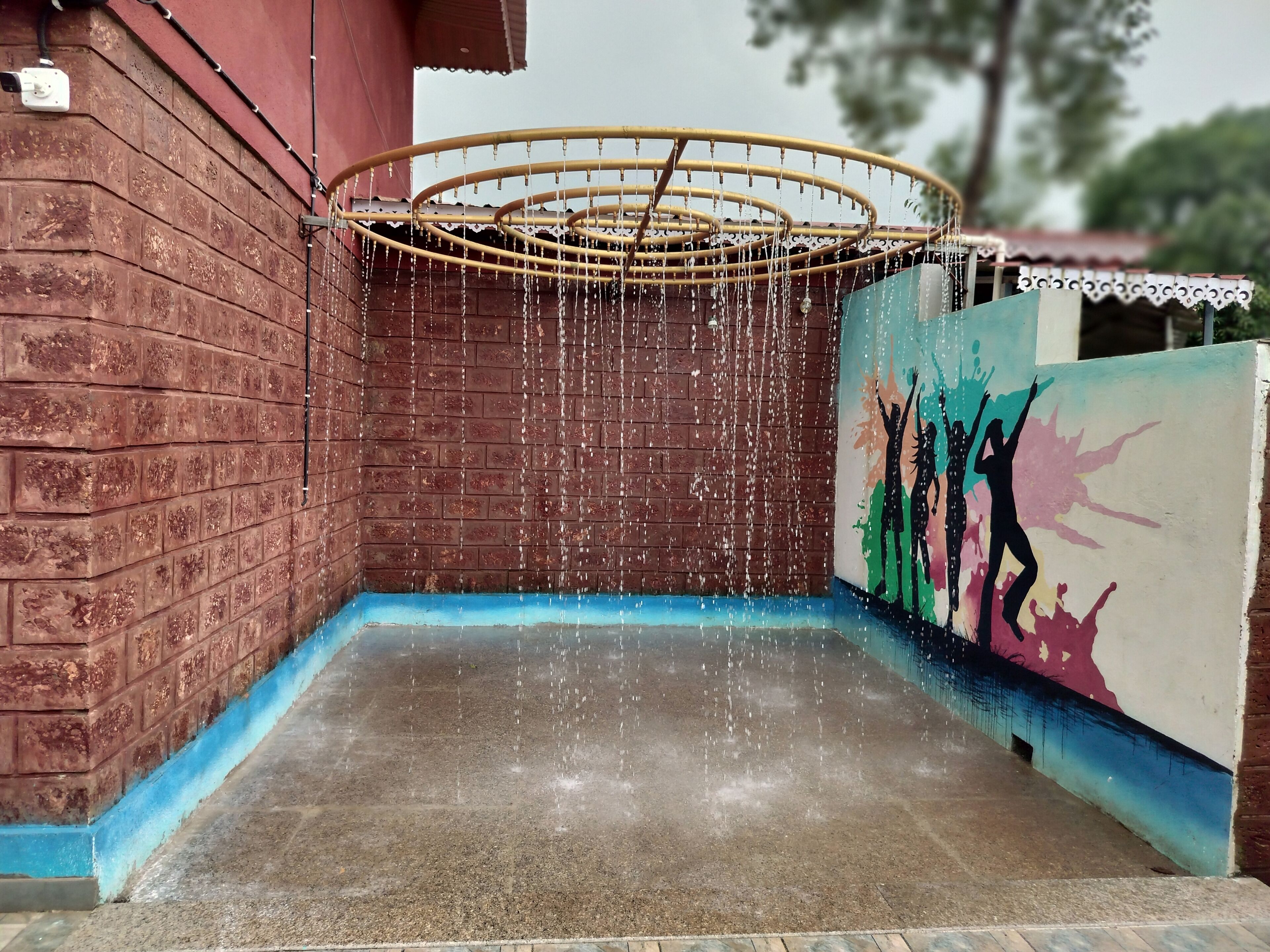 A water feature with a circular structure and a wall with a colorful mural.