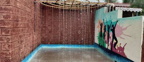 Un élément décoratif aquatique composé d’une structure circulaire et d’un mur orné d’une fresque colorée.