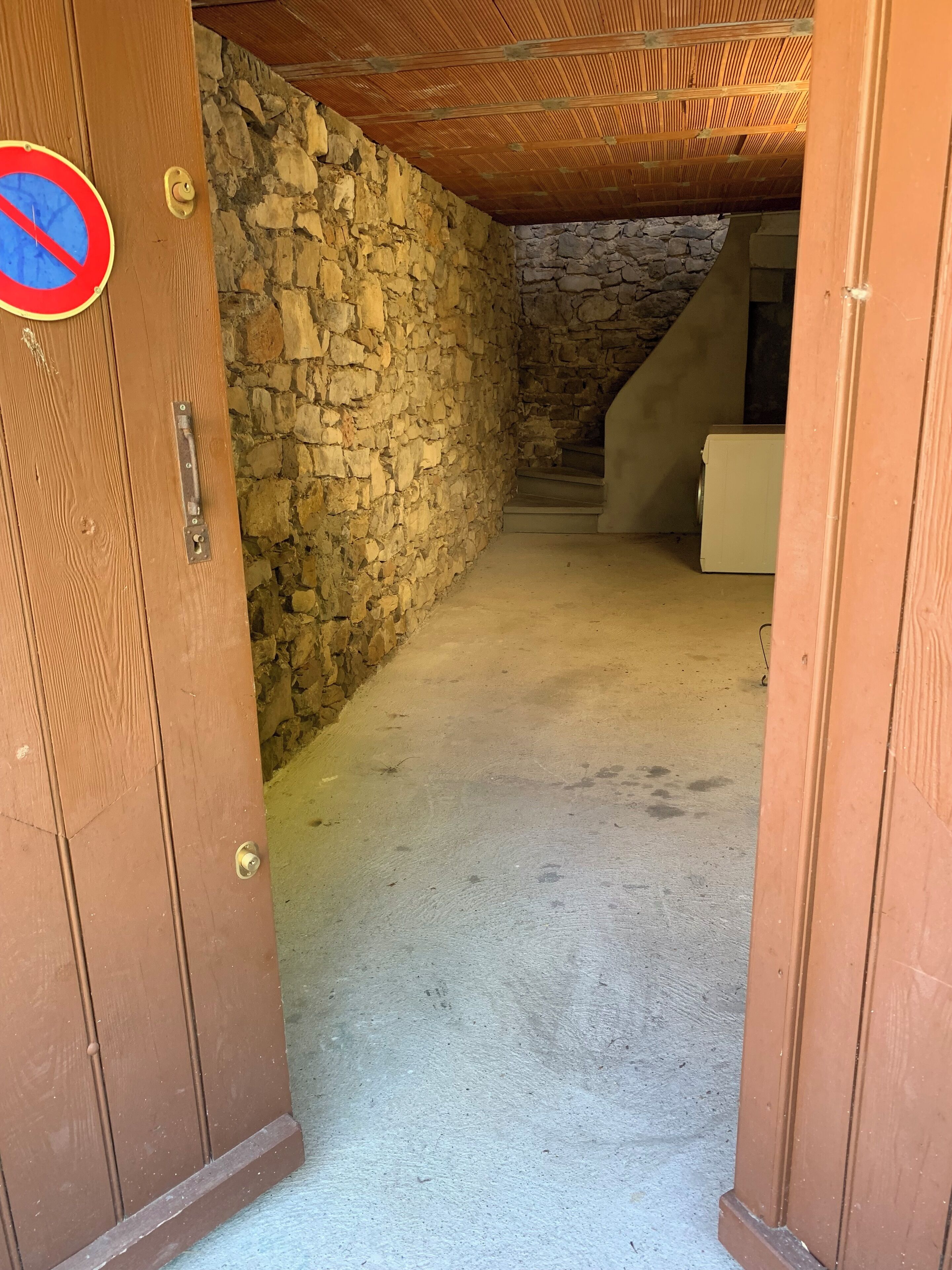 A narrow hallway with a stone wall on one side and a wooden door on the other.