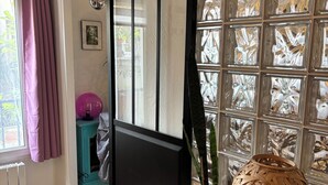 Ein Zimmer mit einer Schiebetür aus Glas, einem Blumentopf, einer dekorativen Lampe und einem Fenster mit einem gemusterten Blick.
