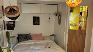 Ein Schlafzimmer mit einem Bett, einer Hängelampe, einer Buddha-Statue und einer Holztür.
