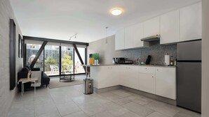 Eine moderne Küche mit weißen Schränken, einem Edelstahl-Kühlschrank und einem großen Fenster mit Blick auf eine Stadtlandschaft.