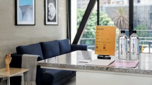 A reception desk with a menu, two bottles, and a framed picture on the wall.