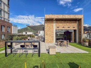 A rooftop terrace with outdoor seating, a pergola, and a view of a mountain.