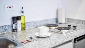 A kitchen counter with a white cup, a bottle of oil, and a small packet.