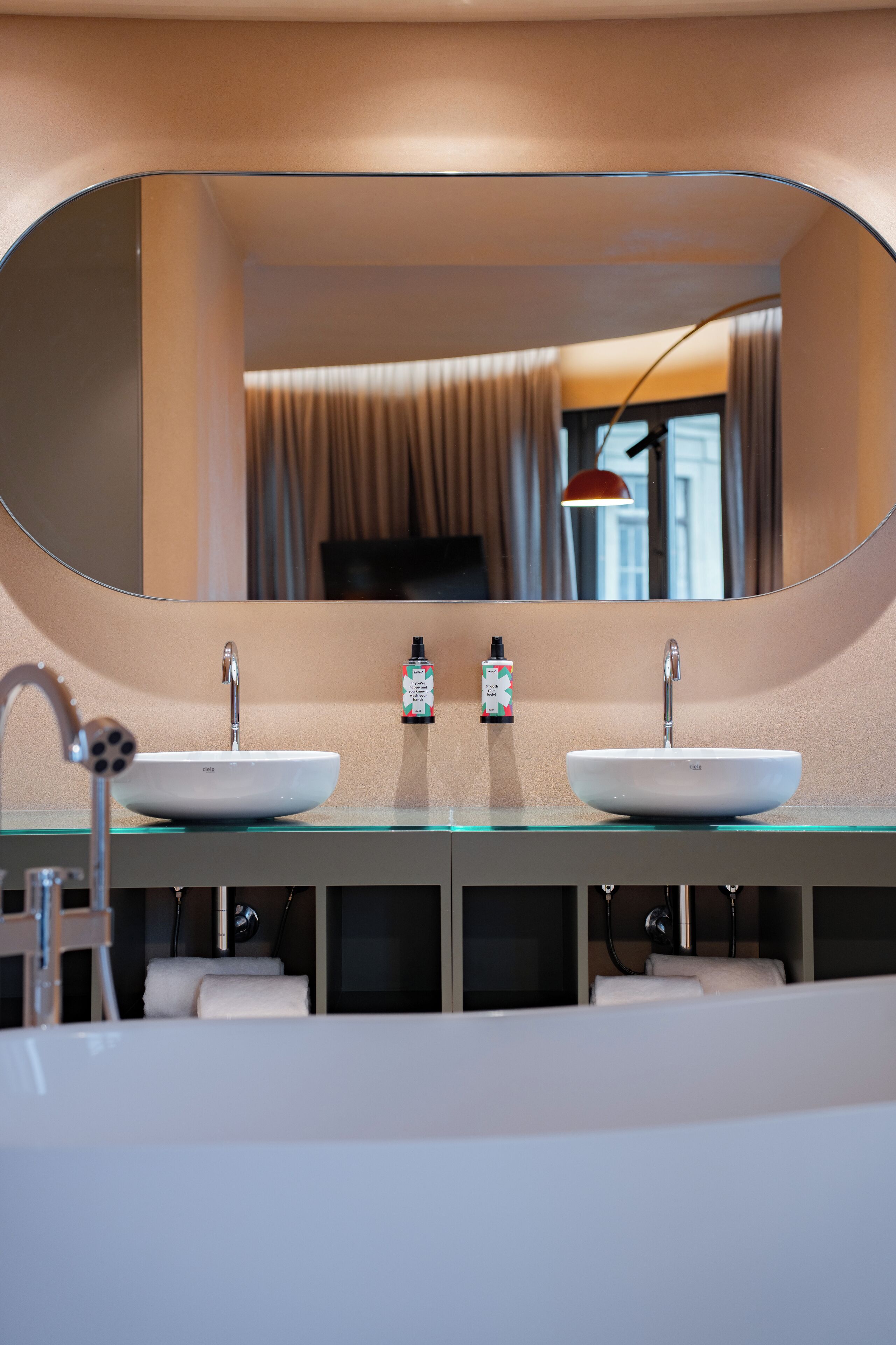 Une salle de bain moderne avec deux lavabos, un grand miroir et un porte-serviettes.