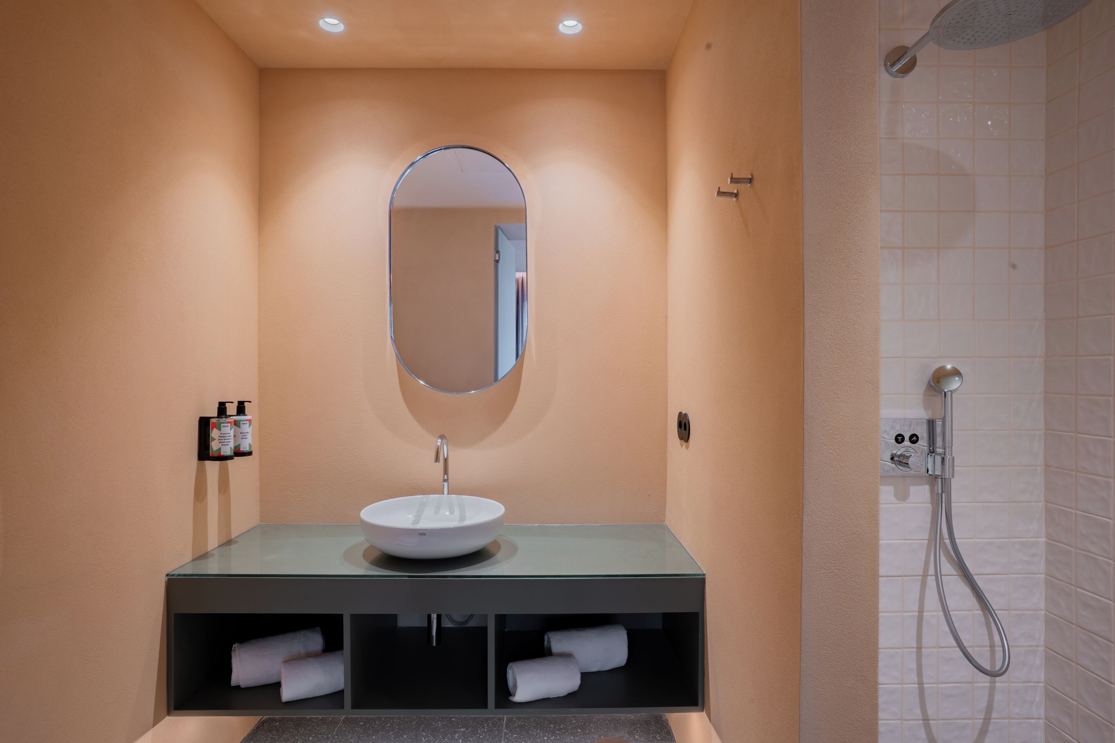 A bathroom with a glass sink, a mirror, and a shower.