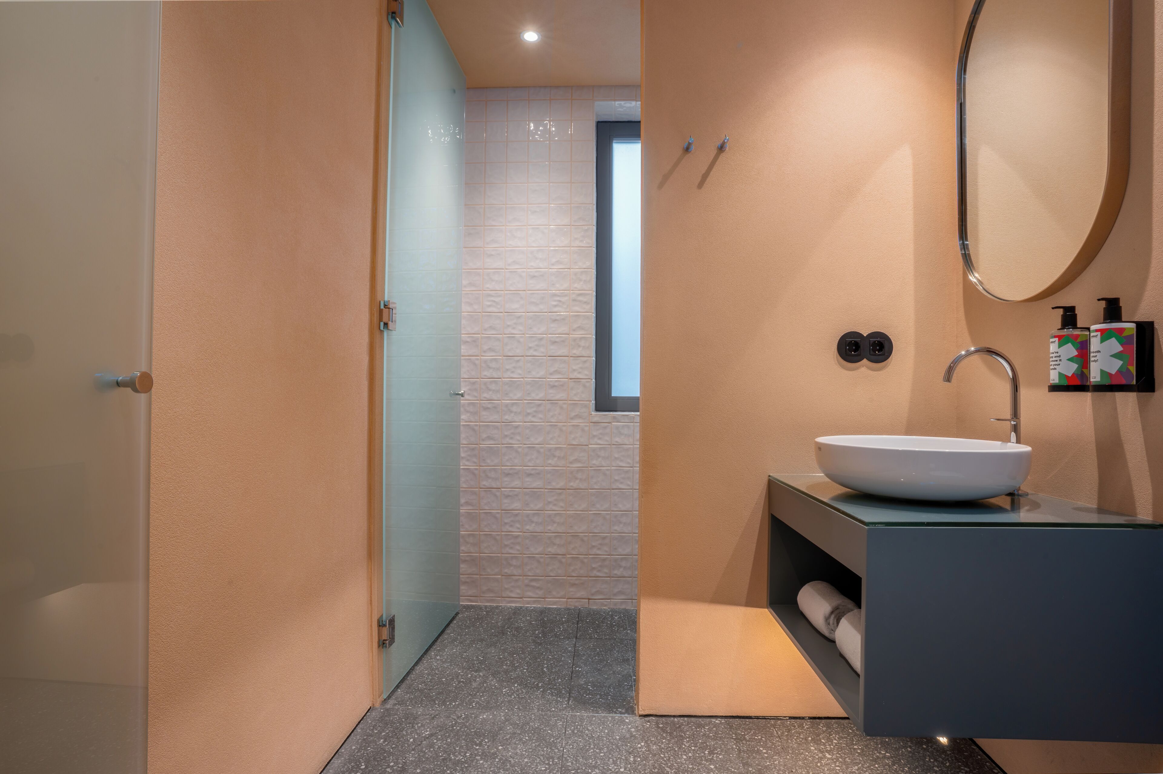 A modern bathroom with a large mirror, a white sink, and a towel rack.