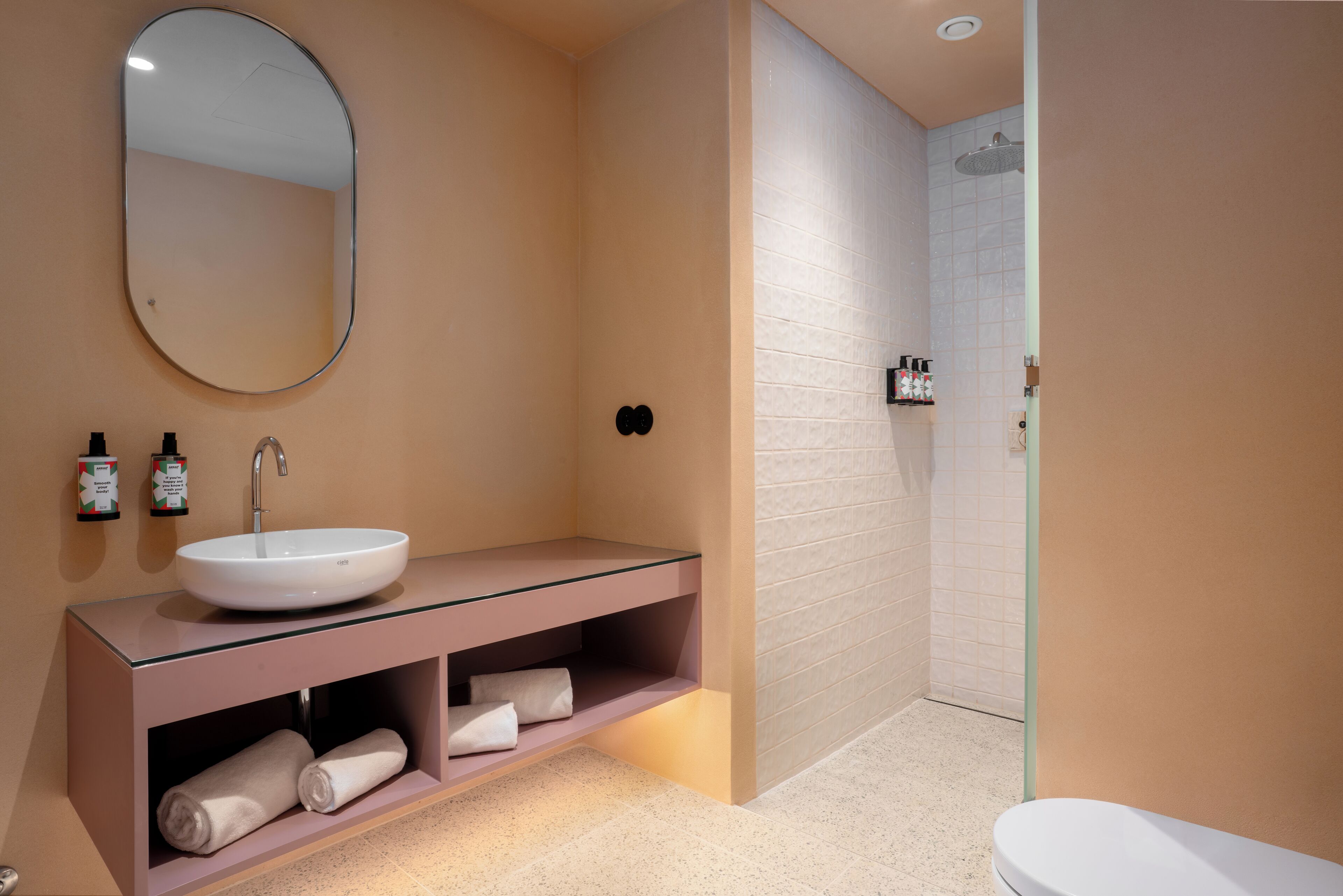 A modern bathroom with a round sink, a mirror, and a shower area.