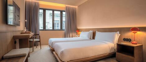 A modern hotel room with a large bed, bedside tables, a desk, and a window with curtains.