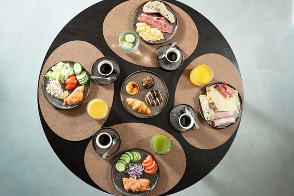 A round table with various breakfast items including eggs, ham, croissants, and fresh fruits. - Akeah Porto Centro (Porto)
