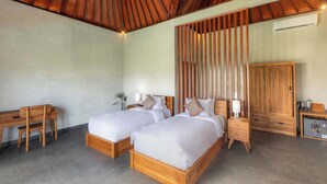A hotel room with two wooden beds, a desk, a wardrobe, and a small kitchenette. - Tumbu Retreat (Karangasem)