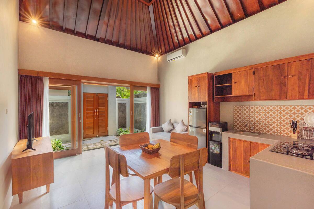 A modern kitchen with wooden cabinets, a dining area with a table and chairs, and a sliding glass door leading to a patio.