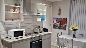 Ett modernt kök med inbyggd mikrovågsugn och ugn, samt en matplats med bord och stolar.