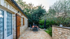 Une terrasse en pierre avec une table et des chaises, une porte en bois et un mur en pierre.