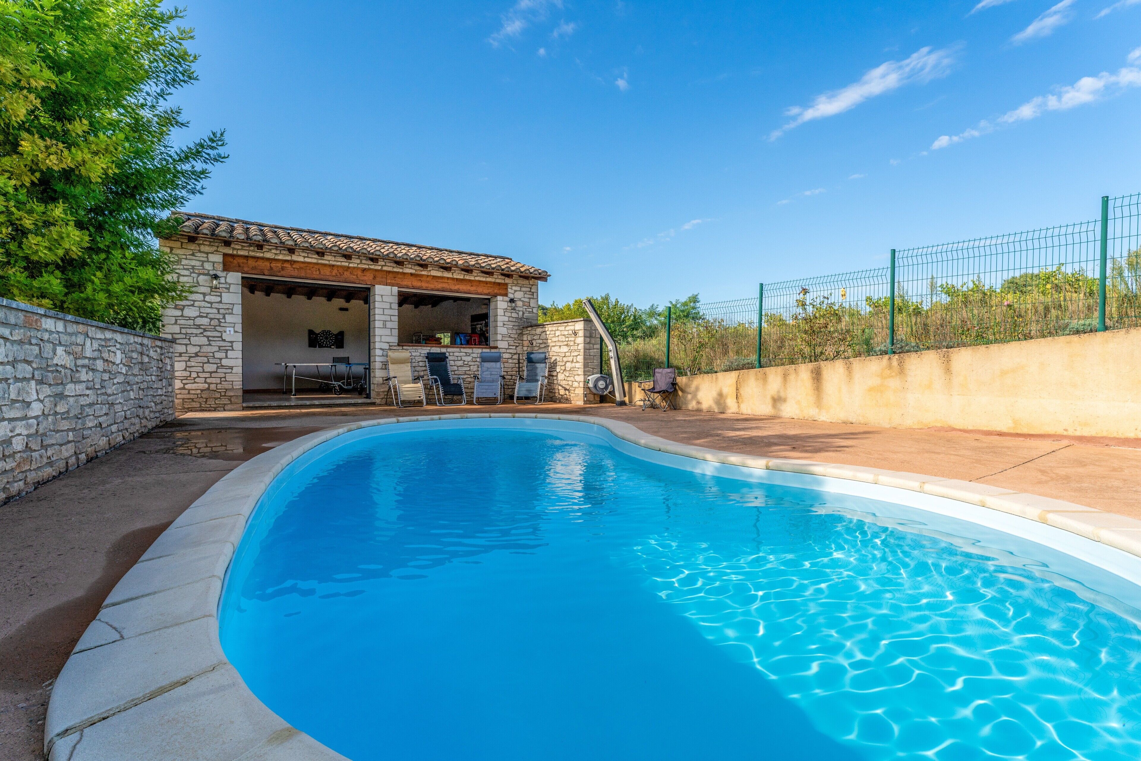 A swimming pool with a stone building and outdoor seating area.