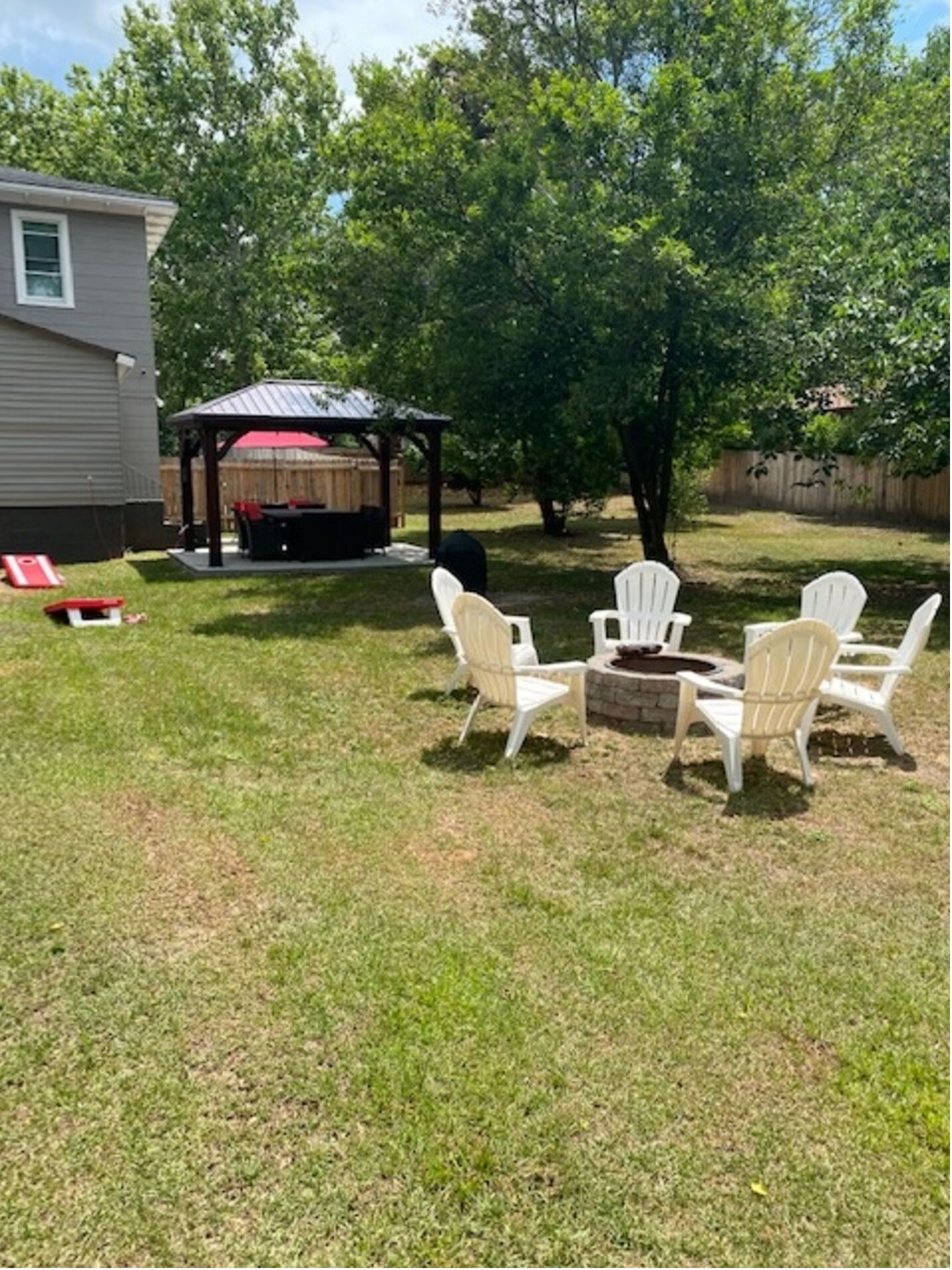 Un patio trasero con zona de barbacoa cubierta, un hogar para fogata y asientos al aire libre.