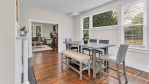 A dining area with a wooden table and chairs, a bench, and a fireplace. - Masters Classic AUGUSTA (Augusta)