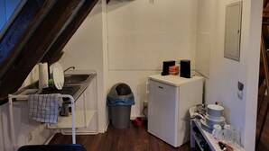 A compact kitchen with a sink, a small refrigerator, and a trash bin. - Half-timbered maisonette in Nürtingen (Nürtingen)