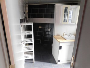Un baño pequeño con un lavamanos blanco, un espejo y un salpicadero de azulejos negros.