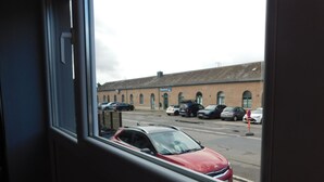 Vista de un estacionamiento con varios autos y un edificio con ventanas arqueadas al fondo.
