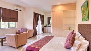 A hotel room with a large bed, a sofa, a small table, and a view of the outside. - OYO 90835 Geopark Hotel Kuah (Langkawi)