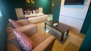 Een moderne hotelkamer met een bed, een bank, een salontafel en een televisie.