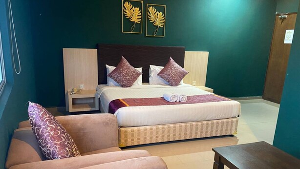 Een hotelkamer met een bed, twee nachtkastjes, een bank en een kleine tafel.