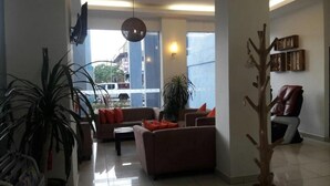 A modern living room with a sofa, armchairs, a coffee table, and a decorative tree sculpture. - OYO 90835 Geopark Hotel Kuah (Langkawi)
