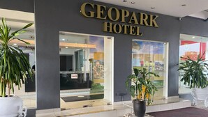 Het uiterlijk van Hotel Geopark, met een duidelijke ingang, potplanten en een goed zichtbaar 'OPEN'-bord.
