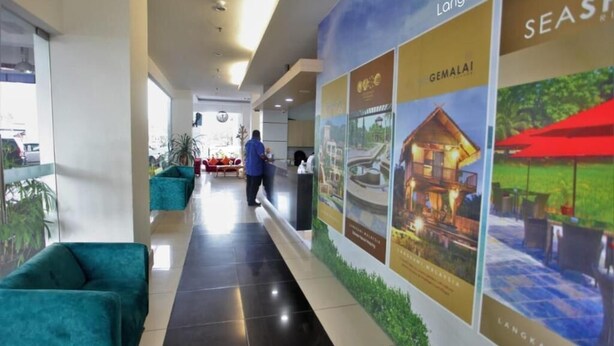 A hotel corridor with teal sofas, a reception desk, and promotional posters for Langkawi and Gemala resorts. - OYO 90835 Geopark Hotel Kuah (Langkawi)