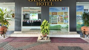 The entrance of the Geopark Hotel with a clear view of the entrance doors, a potted plant, and a display board with information. - OYO 90835 Geopark Hotel Kuah (Langkawi)