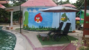 A water park with a mural of Angry Birds, a pool, and lounge chairs. - Capital O 91187 D'dusun Raudhah Chalet (Baling)