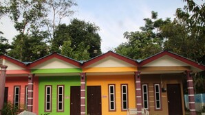 A row of colorful houses with distinct red, green, and yellow facades, each with a front porch and a small bench. - Capital O 91187 D'dusun Raudhah Chalet (Baling)