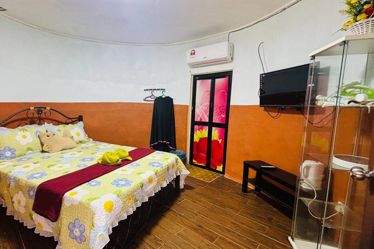 Un dormitorio con cama, televisor, armario y puerta con un ventanal colorido.