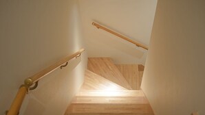 A wooden staircase with a handrail and a light source at the top. - Kyomachiya SEN Gojo-Ikkanmachi ANNEX (Kyoto)