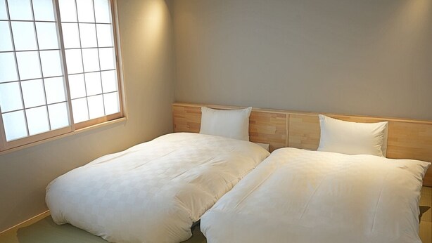 A room with two beds, a wooden headboard, and a window with a grid pattern. - Kyomachiya SEN Gojo-Ikkanmachi ANNEX (Kyoto)