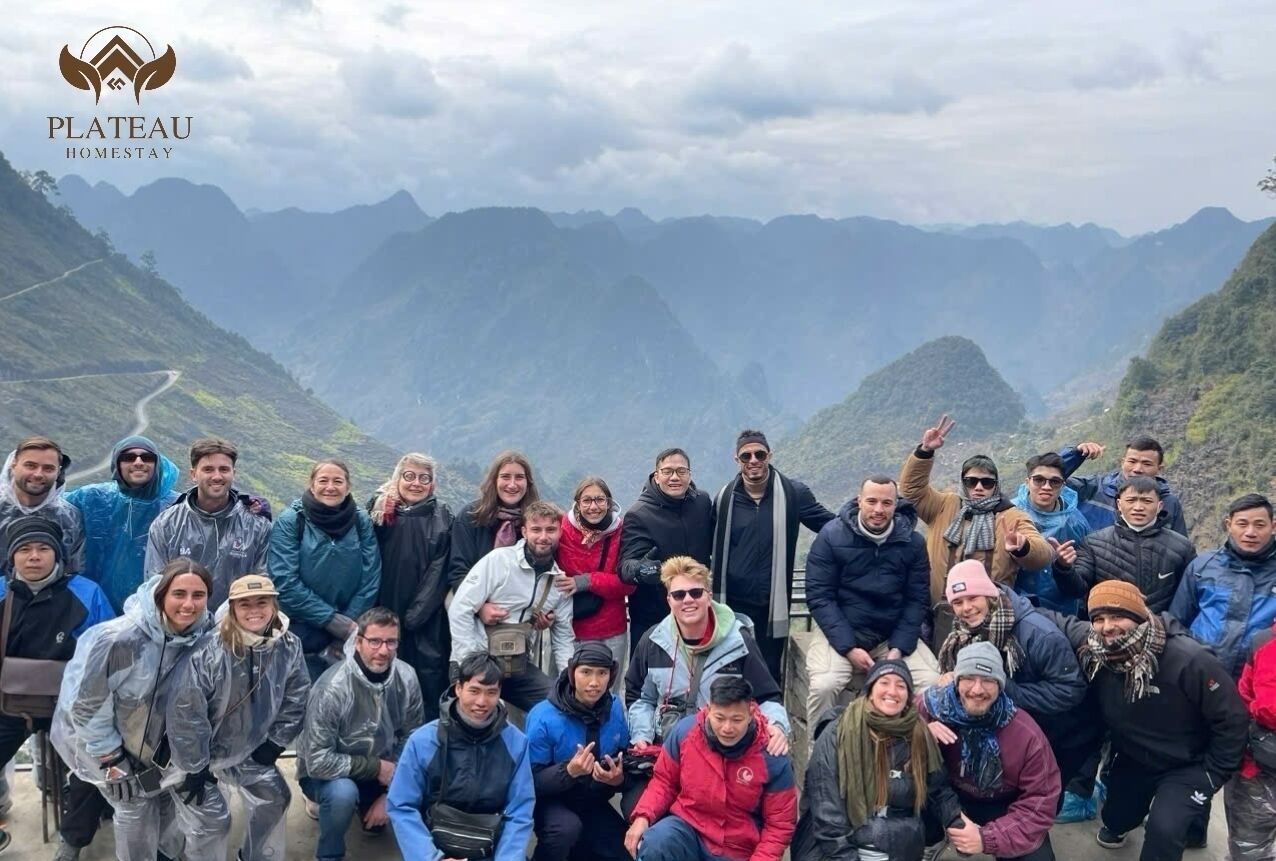 Un groupe de personnes se trouve dans une région montagneuse, le long d’une route sinueuse.