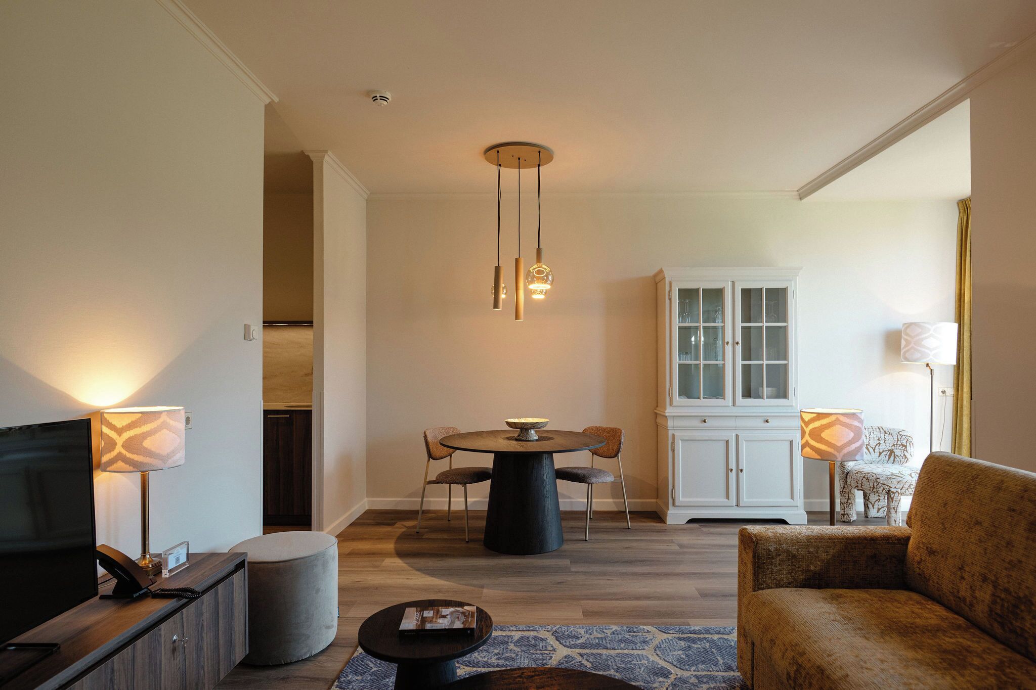 A modern living room with a TV, sofa, dining table, chairs, and a cabinet.