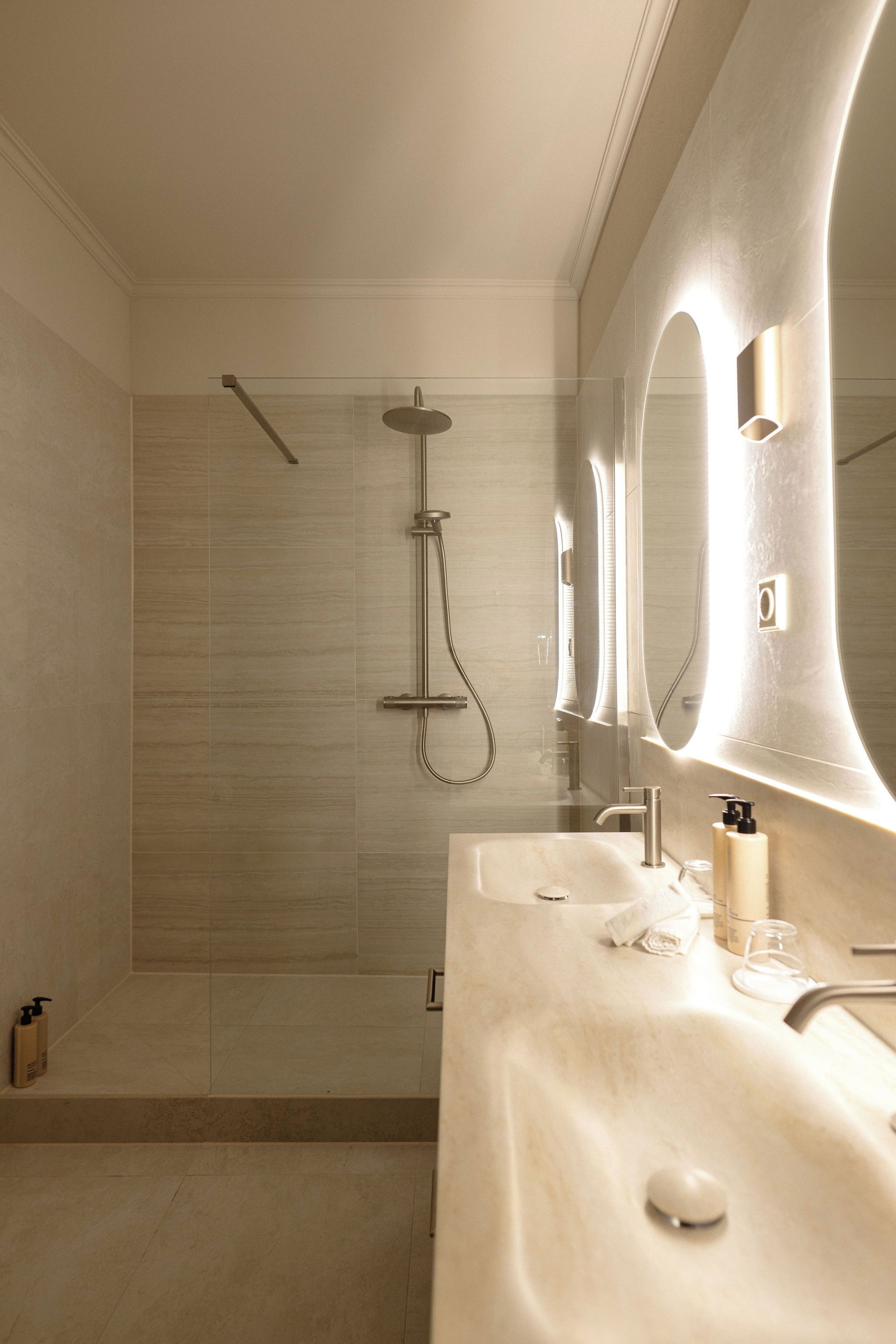 A modern bathroom with a shower, a sink, and a large mirror.