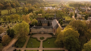 An aerial view of a large estate with a central building surrounded by manicured gardens and a formal lawn.