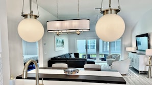 Una cocina moderna con una isla central, pileta de acero inoxidable e iluminación colgante.