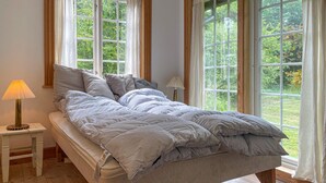 A bedroom with a bed, two bedside tables, a lamp, and large windows with curtains. - Cozy home in Sjællands Odde with WiFi (Sjællands Odde)