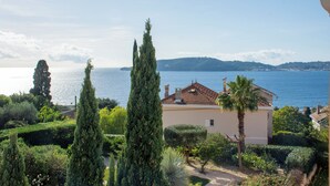 Une propriété située sur la côte, avec une maison de style méditerranéen, un jardin luxuriant et une vue sur la mer.