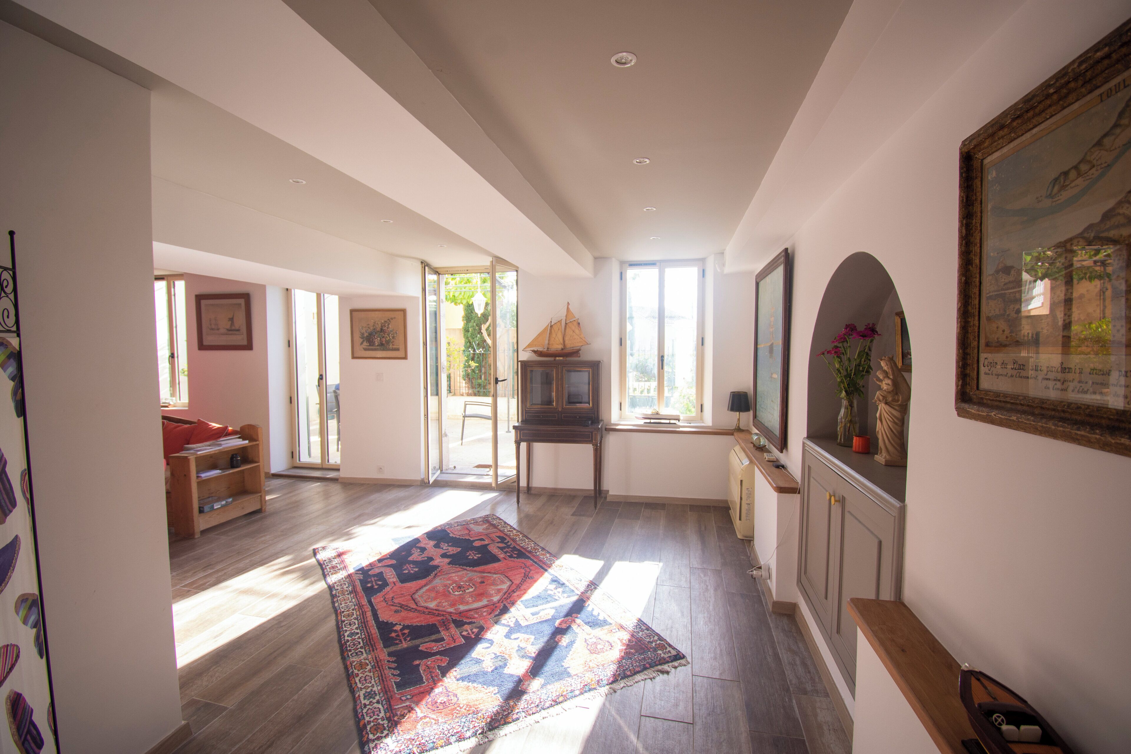 Un vaste espace de vie agrémenté d’un grand tapis, de meubles en bois et d’un téléviseur.